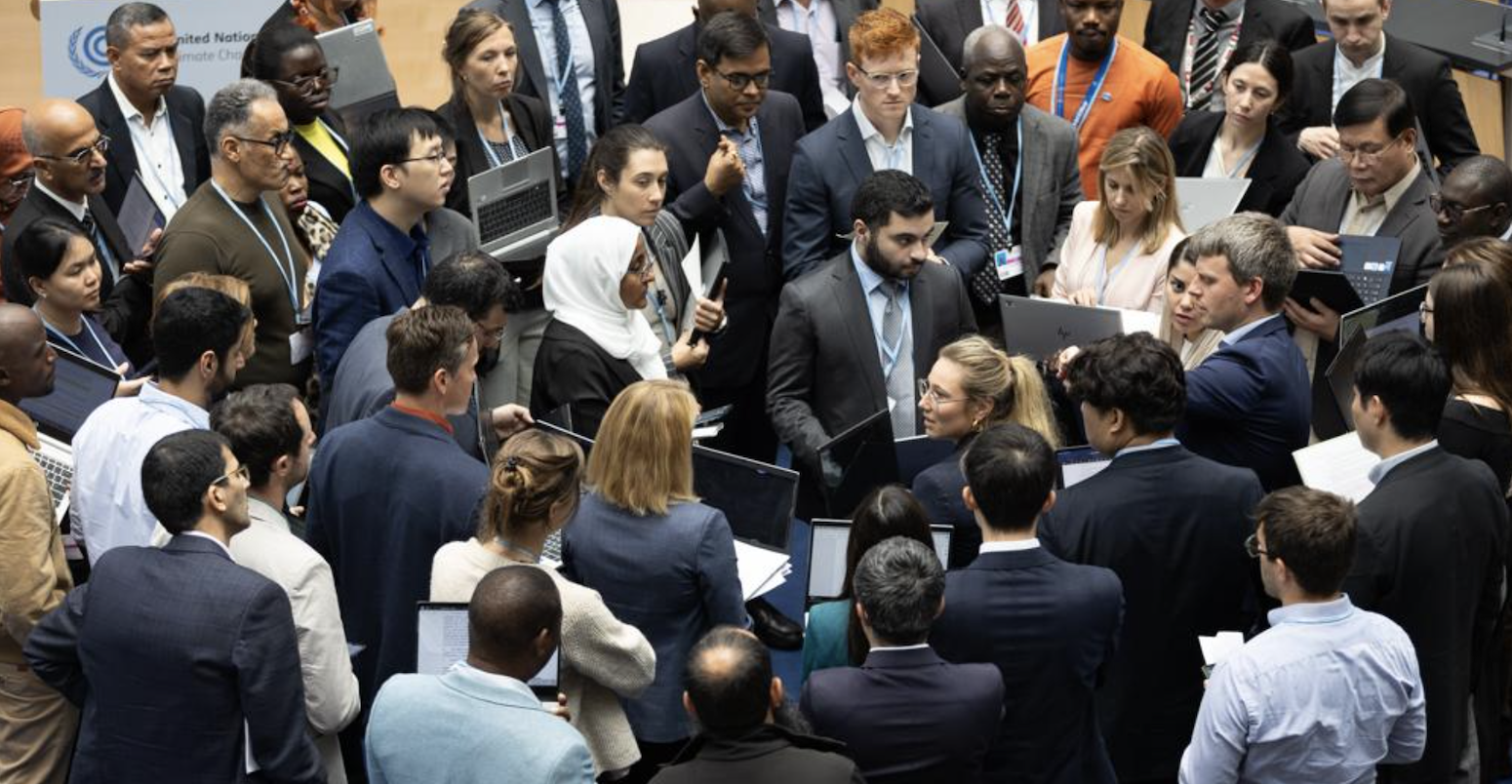 Delegates huddle during consultations on Paris Agreement Article 6.8.